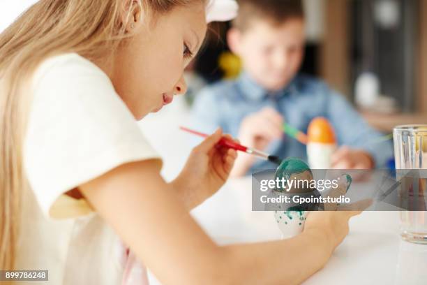 girl painting hard boiled easter egg green at table - kid boiled egg bildbanksfoton och bilder