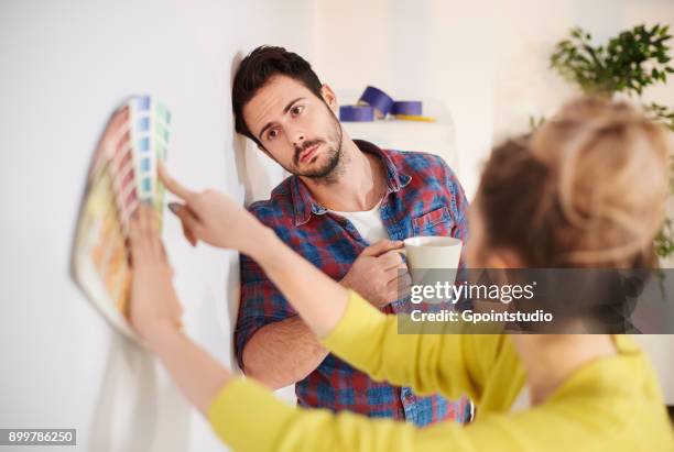 young couple in new home, looking at paint swatches - colour selection stock pictures, royalty-free photos & images