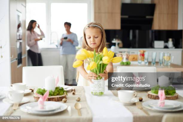 girl arranging yellow tulips at easter dining table - easter poland stock pictures, royalty-free photos & images