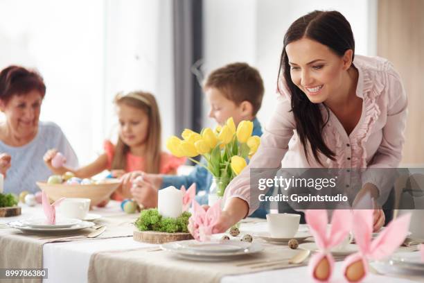 woman and family preparing place settings at easter dining table - easter poland stock pictures, royalty-free photos & images