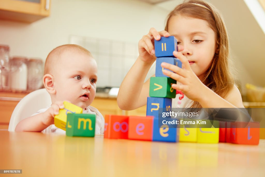 Baby boy with sister, playing with colourful blocks