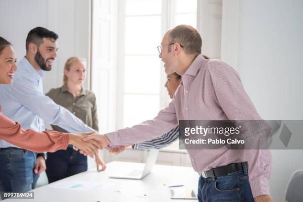 businesswomen and men shaking hands at boardroom table - formal shirt stock pictures, royalty-free photos & images