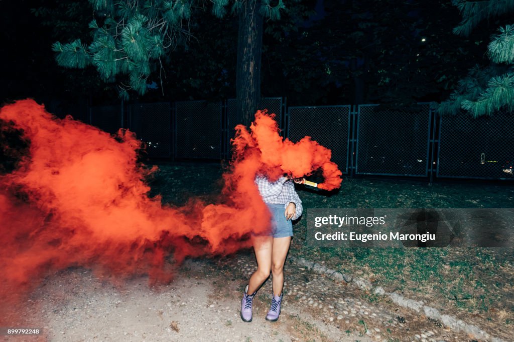 Woman holding flare in park at night