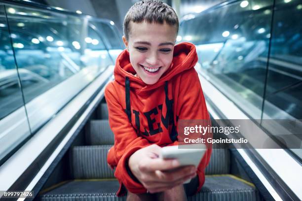 short haired young woman moving down underground station escalator looking at smartphone - daily life in warsaw photos et images de collection