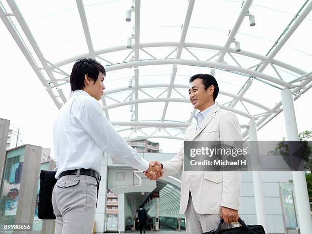 businessman who shakes hands - low angle view of two businessmen standing face to face outdoors stock pictures, royalty-free photos & images