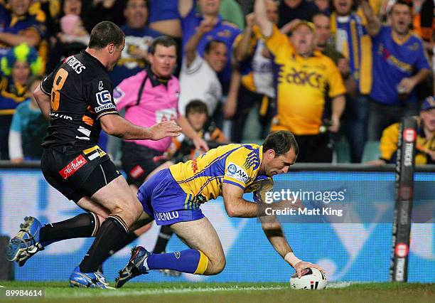 Luke Burt of the Eels is kneed in the back by Bryce Gibbs of the Tigers as he scores a try during the round 24 NRL match between the Wests Tigers and...