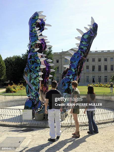 Des personnes regardent la sculpture de l'artiste plasticien Guillaume Renou intitulée "Crocodile", le 31 juillet 2009 dans les jardins du Palais...