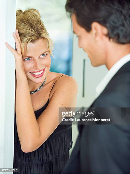 smiling blond woman opening door to boyfriend - temptation stock-fotos und bilder