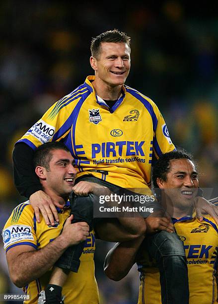 Boxer Danny Green is carried from the field by Tim Mannah and Fuifui Moimoi of the Eelsafter the round 24 NRL match between the Wests Tigers and the...