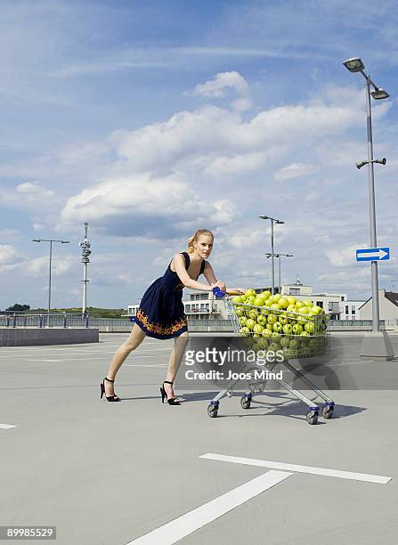 young woman pushing shopping cart - apple arrow stock-fotos und bilder