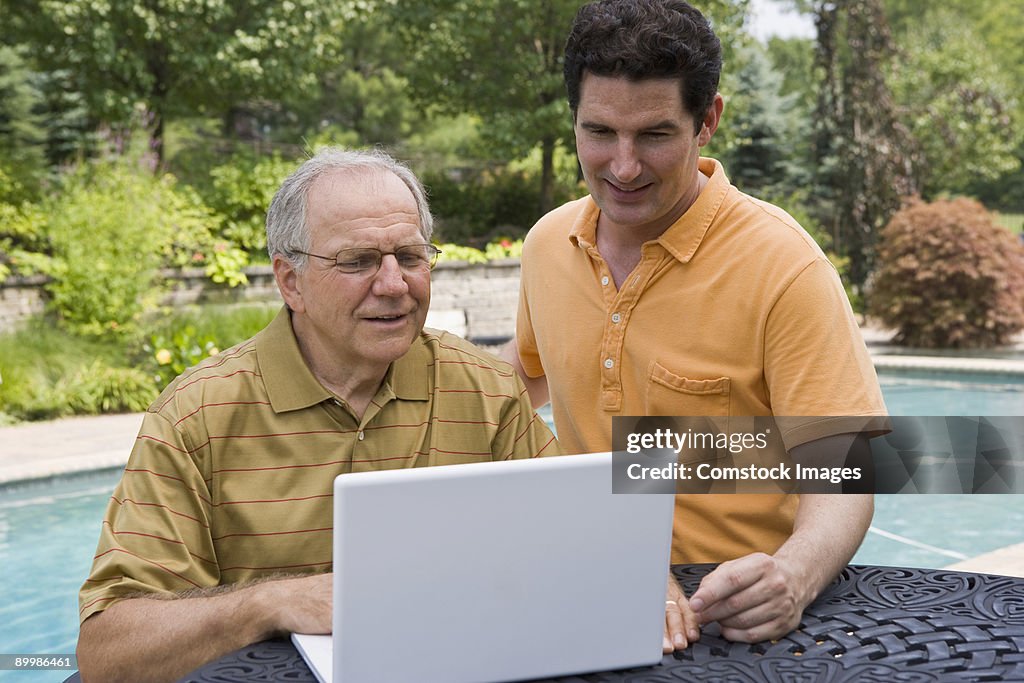Father and son using computer outside