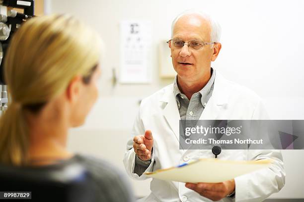 mature doctor having a discussion with patient - eye doctor and patient stock pictures, royalty-free photos & images