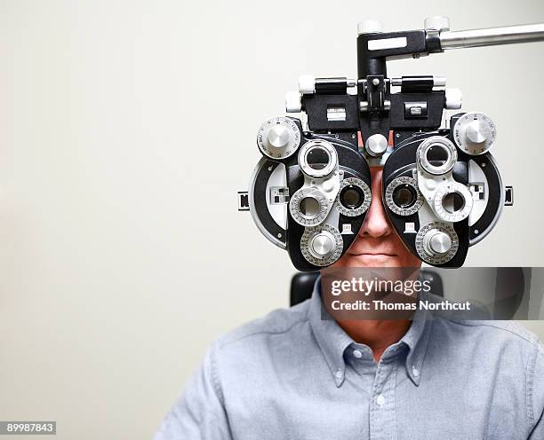 mature man looking through phoroptor - eye test 個照片及圖片檔