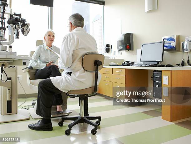 ein arzt und patient diskutieren ihre vision zu erfüllen - arztstuhl stock-fotos und bilder