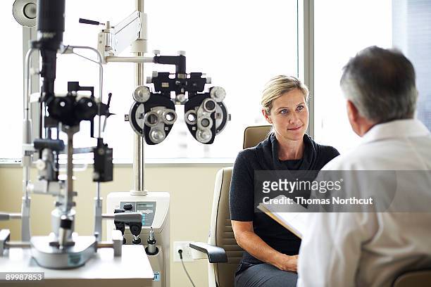 una mujer escucha su opthamologist - optician fotografías e imágenes de stock