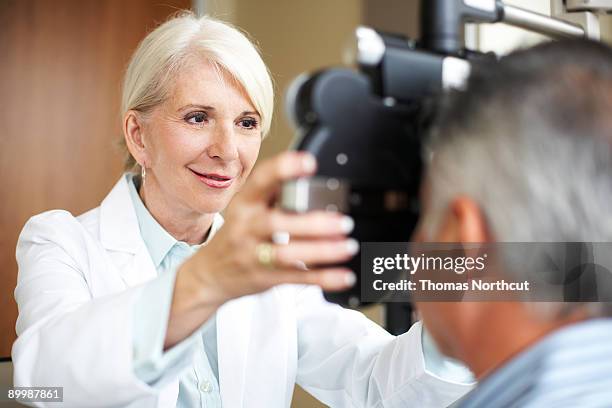 maduro opthamologist controles la visión de un hombre maduro - optician fotografías e imágenes de stock