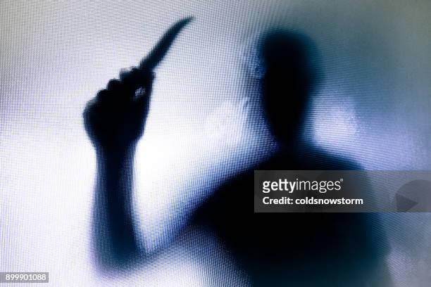 violent threatening silhouette of man wielding a knife behind frosted glass window - killing imagens e fotografias de stock