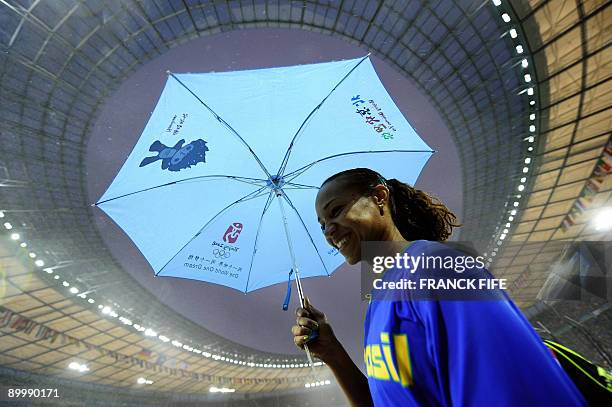 Brazil's Maurren Higa Maggi hides under an umbrella of the 2008 Beijing Olympic Games as as rain pours down during the women's long jump qualifying...