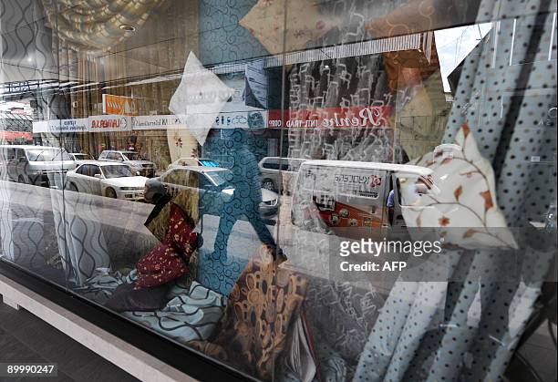 The image of a man pushing a trolley with marchandise is reflected by the window of a store at the free zone of Colon, 100 km north of Panama City...