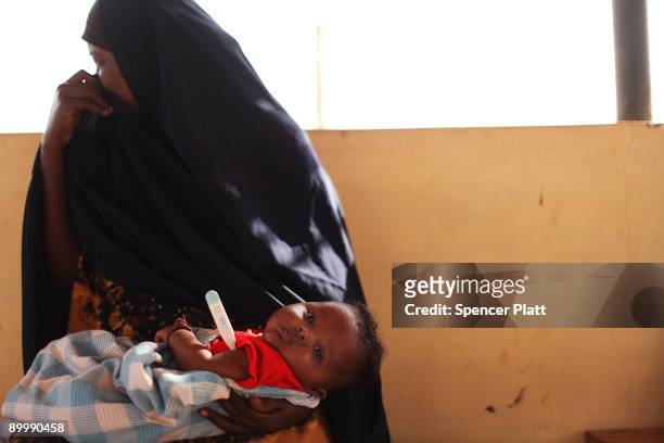 Saper Nasra Hassan, 4 months, sits in his mother's lap while his temperature is taken inside a Doctors Without Borders medical station August 21,...