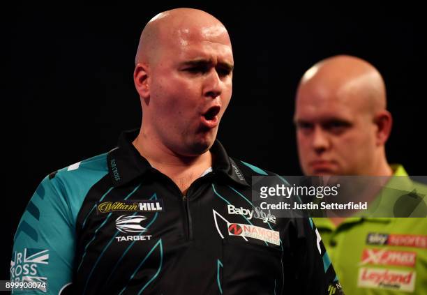 Rob Cross celebrates during his Semi Final Match as Michael van Gerwen looks on during the 2018 William Hill PDC World Darts Championships at...