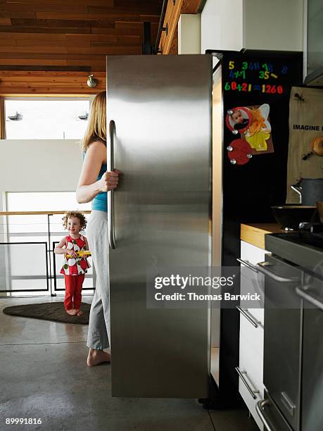 mother reaching in refrigerator in home - open day 3 stock pictures, royalty-free photos & images