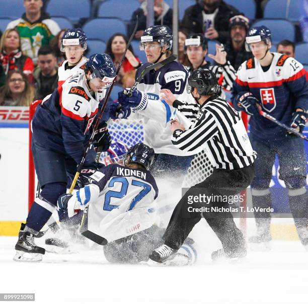 Janne Kuokkanen of Finland comes to the aid of Joni Ikonen who was checked to the ice by Martin Bodák of Slovakia during an altercation in the third...