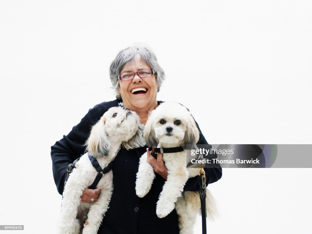 Mature woman laughing holding two dogs