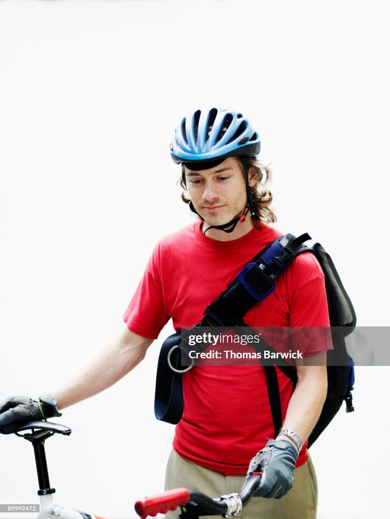 Male bicycle messenger holding bike