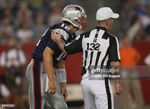 Tom Brady of the New England Patriots holds his knee after a hit by the Cincinnati Bengals as referee John Parry attends to him during the preseason...