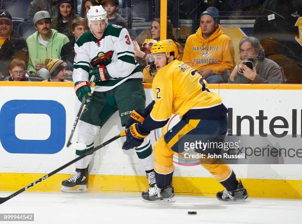Charlie Coyle of the Minnesota Wild passes the puck behind Anthony Bitetto of the Nashville Predators during an NHL game at Bridgestone Arena on...