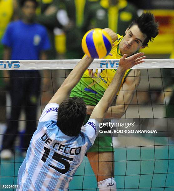 Brazil's Giba spikes the ball against Argentina`s Luciano De Cecco during their South American Final men's volleyball match in Bogota on August 21,...