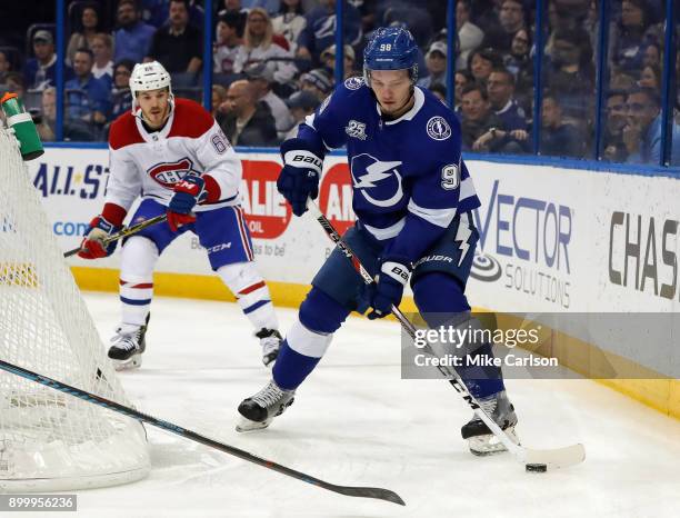 Mikhail Sergachev of the Tampa Bay Lightning looks to move the puck as Andrew Shaw of the Montreal Canadiens defends during the first period at...