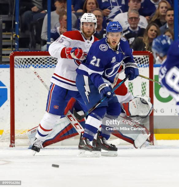 Brayden Point of the Tampa Bay Lightning and Joe Morrow of the Montreal Canadiens look at an approaching shot during the first period at Amalie Arena...