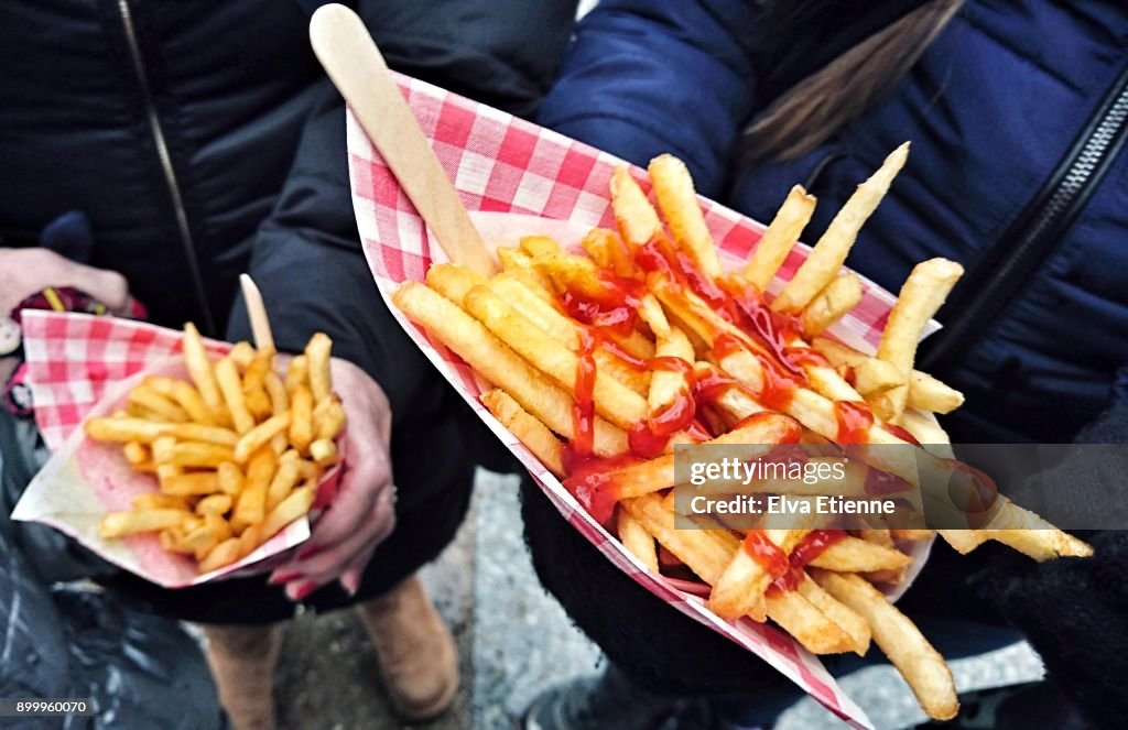 Two people eating chips outdoors at a street market
