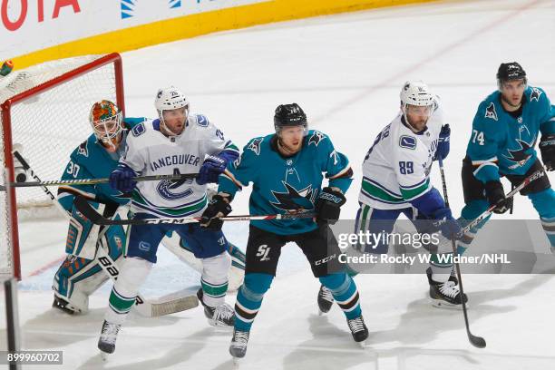 Aaron Dell, Tim Heed and Dylan DeMelo of the San Jose Sharks defend against Thomas Vanek and Sam Gagner of the Vancouver Canucks at SAP Center on...