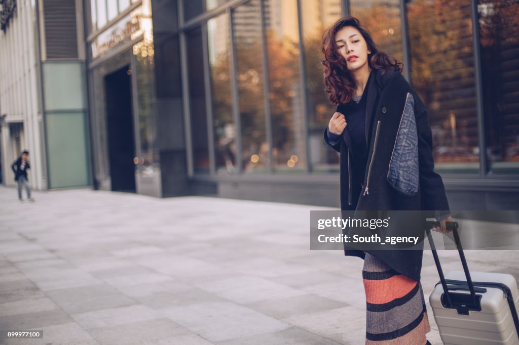 Beautiful woman standing on the street with suitcase