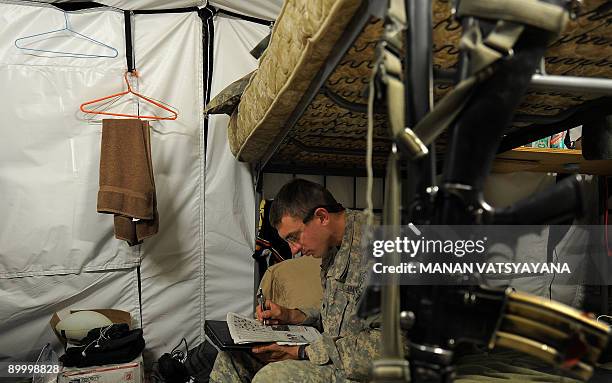 Specialist Robert Kiefer from the 1st Platoon Alpha 3-71 Cavalry solves a crossword puzzle as he rests in his barracks before leaving for a mission...