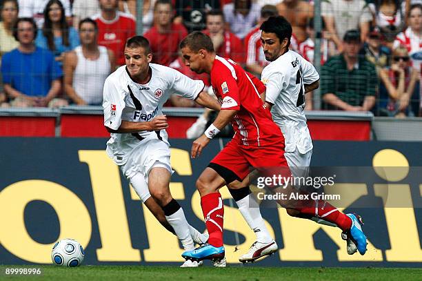 Lukas Podolski of Koeln is challenged by Alexander Meier and Chris of Frankfurt during the Bundesliga match between 1. FC Koeln and Eintracht...