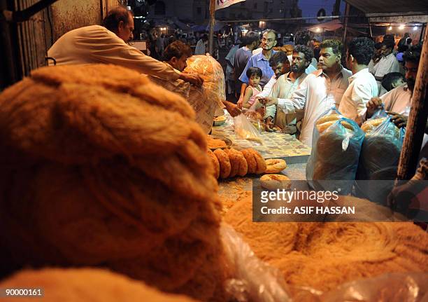 Pakistani Muslims purchase "Khajla and Phaini," sweet dish which is widely popular during the holy month of Ramadan, at a shop in Karachi on August...