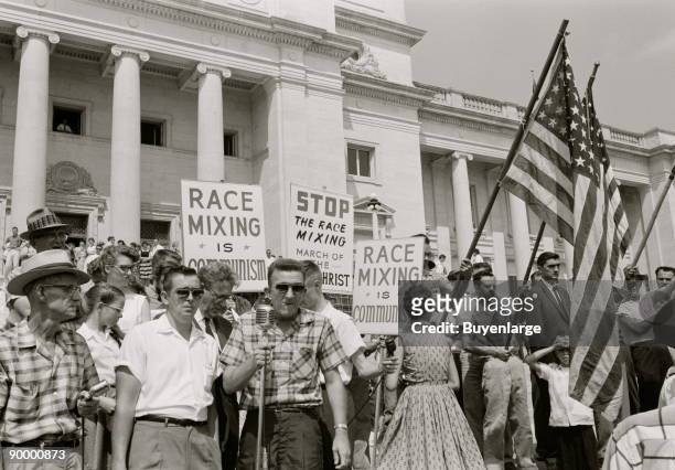 People holding signs and American flags protesting the admission of the "Little Rock Nine" to Central High School.