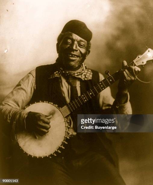Negro man seated and holding banjo.