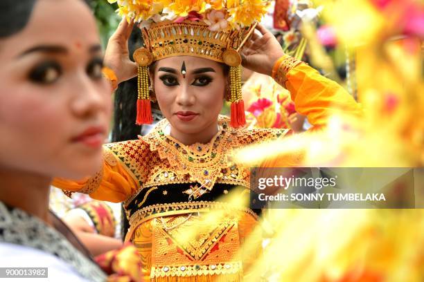 Balinese girl adjusts her headdress before taking part in a traditional dance during in a cultural parade at a festival to mark the New Year in...