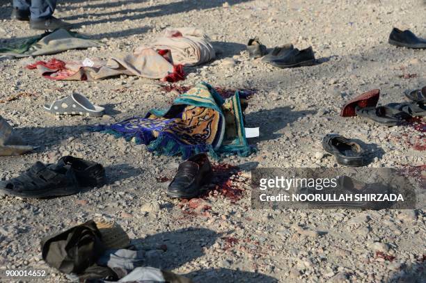 Belongings of blast victims lay in the ground at the scene of a suicide attack that targeted a funeral ceremony in Jalalabad on December 31, 2017. -...
