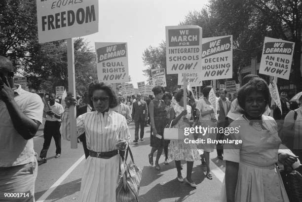 Procession of African Americans carrying signs for equal rights, integrated schools, decent housing, and an end to bias.