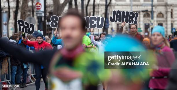 Runners hold up signs reading "Happy New Year" while taking part in the 41st Vienna New Year's Eve run on the Ringstrasse on December 31, 2017 in...