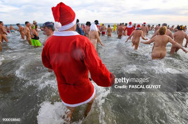 People take part in a traditional sea bathing as part of new years celebrations on December 31, 2017 on a nudist beach in Le Cap d'Agde, southern...