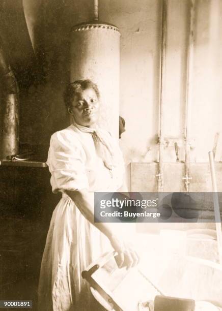 African American woman, three-quarter length portrait, standing, facing front, doing laundry at wash tub, in Washington, D.C.