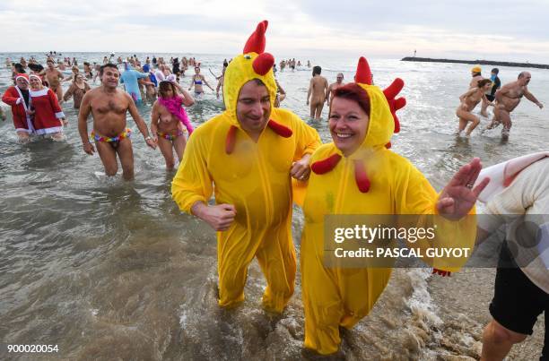 People take part in a traditional sea bathing to mark new-year's end on December 31, 2017 on a nudist beach in Le Cap d'Agde, southern France. / AFP...