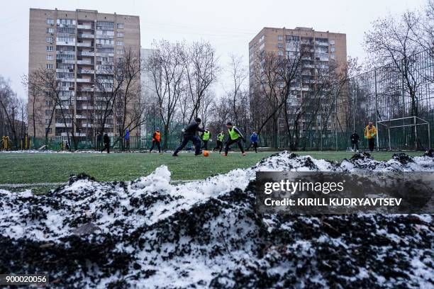 Men play football on a synthetic pitch close to a school in Moscow suburb on December 31, 2017. / AFP PHOTO / Kirill KUDRYAVTSEV